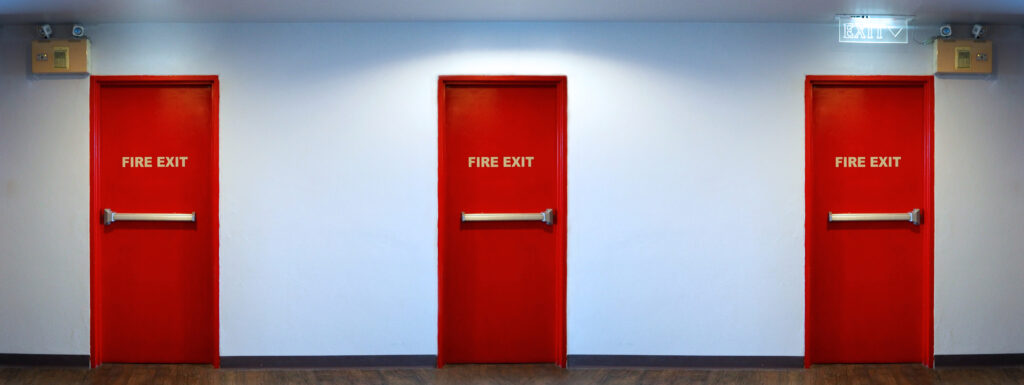 Three red fire exit doors in a hallway, showcasing fire rated door design by a fire rated door supplier in Malaysia.